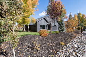 Rear view of house featuring board and batten siding, a lawn, and a garage