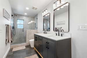 Full bathroom with double vanity, a stall shower, and recessed lighting