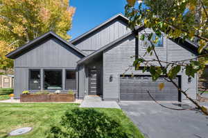 View of front of property with asphalt driveway, a front lawn, and a garage