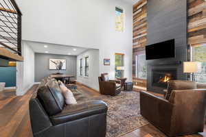 Living area featuring dark wood-style floors, a high ceiling, a large fireplace, plenty of natural light, and recessed lighting