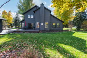 Back of property featuring a yard, a deck, and a chimney