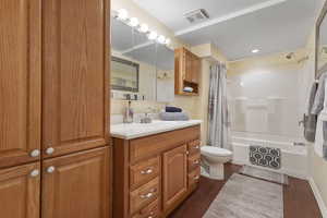 Full bath with shower / tub combo, dark wood-style flooring, and vanity