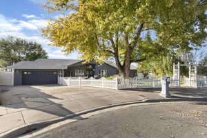 Ranch-style house featuring concrete driveway, a fenced front yard, a garage, and a shingled roof