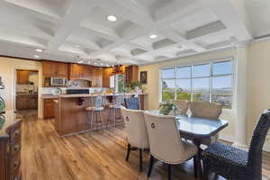 Dining area featuring light wood finished floors, beam ceiling, recessed lighting, coffered ceiling, and ornamental molding