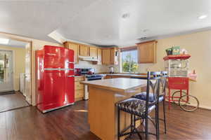 Kitchen featuring freestanding refrigerator, dark wood finished floors, white gas range, light countertops, and crown molding