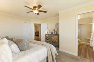 Bedroom with crown molding, carpet flooring, a ceiling fan, wood finished floors, and ensuite bathroom