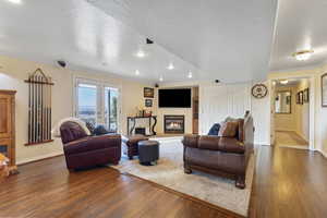 Living area featuring a glass covered fireplace, a textured ceiling, wood-type flooring, ornamental molding, and recessed lighting