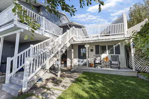 Exterior space with a wooden deck, a lawn, and stairs