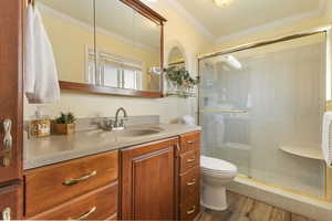 Bathroom with vanity, light wood finished floors, ornamental molding, and a shower stall