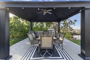 Deck with outdoor dining space, ceiling fan, a gazebo, and exterior kitchen