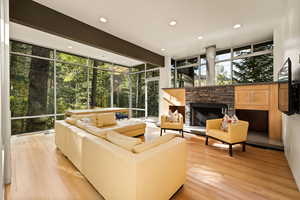 Living room featuring floor to ceiling windows, a stone fireplace, recessed lighting, light wood finished floors, and plenty of natural light