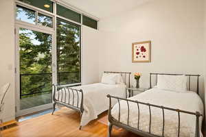 Bedroom featuring wood finished floors, access to exterior, and floor to ceiling windows