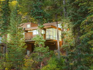 Back of house with a wooded view and a sunroom