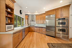 Kitchen with appliances with stainless steel finishes, recessed lighting, a warming drawer, light wood finished floors, and open shelves
