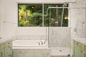 Full bathroom featuring vanity, a garden tub, and a marble finish shower