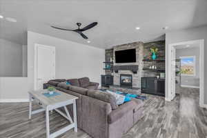 Living room with light wood-style floors, a fireplace, recessed lighting, and ceiling fan