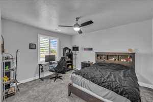 Bedroom with a desk, carpet floors, a textured ceiling, and ceiling fan