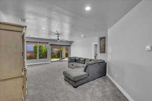 Living area with light colored carpet, ceiling fan, recessed lighting, and a textured ceiling