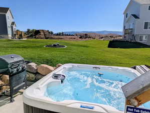 View of green lawn featuring a hot tub and a mountain view