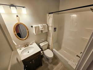 Full bath featuring shower / bath combination with curtain, vanity, and dark wood finished floors