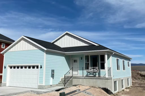 View of front facade with covered porch, board and batten siding, roof with shingles, an attached garage, and concrete driveway