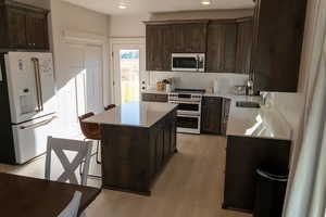 Kitchen featuring dark brown cabinetry, high end fridge, range with two ovens, and a kitchen bar