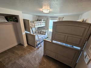 Bedroom featuring dark colored carpet and a textured ceiling
