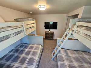 Bedroom featuring light colored carpet and a textured ceiling