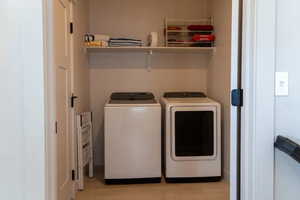 Laundry room featuring washing machine and clothes dryer and light wood finished floors
