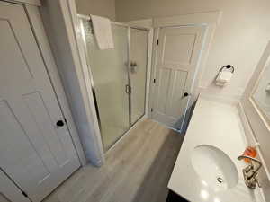 Full bath featuring vanity, a shower stall, and light wood-type flooring