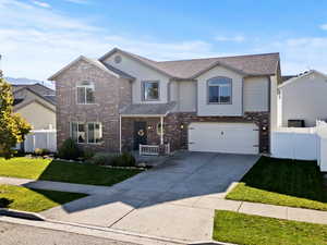 Traditional home with concrete driveway, brick siding, an attached garage, covered porch, and roof with shingles