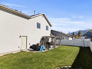 Back of house featuring a mountain view, a fenced backyard, a pergola, and a patio