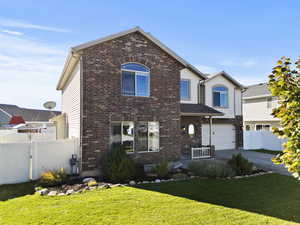 Traditional-style house with driveway, brick siding, covered porch, and an attached garage