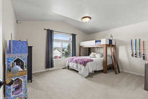 Bedroom with light colored carpet and lofted ceiling