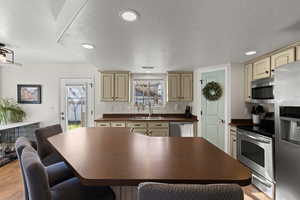 Kitchen featuring stainless steel appliances, dark countertops, light wood-style floors, recessed lighting, and a textured ceiling