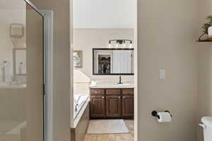 Full bathroom featuring a bath, a shower stall, a spacious closet, vanity, and light tile patterned floors