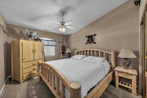 Bedroom featuring a textured ceiling, dark carpet, a ceiling fan, and lofted ceiling