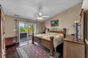 Bedroom with vaulted ceiling, access to exterior, dark wood-style flooring, ceiling fan, and a textured ceiling
