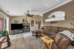 Living room featuring a textured ceiling, vaulted ceiling, a premium fireplace, arched walkways, and built in features