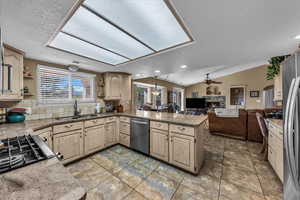 Kitchen with light brown cabinets, backsplash, a peninsula, stainless steel appliances, and plenty of natural light