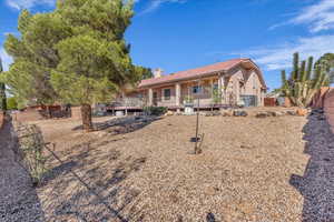 Rear view of house featuring a fenced backyard, a chimney, stucco siding, and a porch