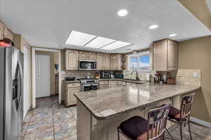 Kitchen featuring a peninsula, stainless steel appliances, a kitchen breakfast bar, decorative backsplash, and a textured ceiling