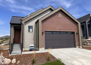 Single story home with driveway, a metal roof, an attached garage, and brick siding