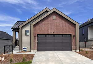 Ranch-style home with driveway, a garage, brick siding, a standing seam roof, and a metal roof