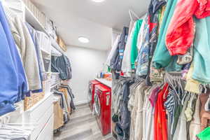 Walk in closet with separate washer and dryer and light wood-type flooring