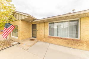 View of exterior entry featuring brick siding and a patio area