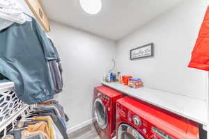 Washroom with washer and clothes dryer, light wood-type flooring, and a textured wall