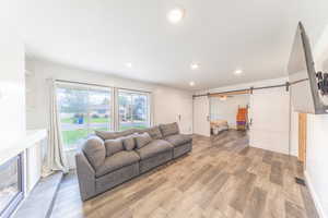 Living room with light wood finished floors, recessed lighting, and a barn door