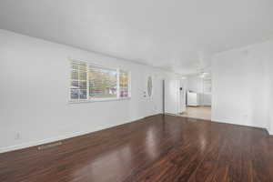 Unfurnished room featuring plenty of natural light, wood finished floors, independent washer and dryer, and ceiling fan