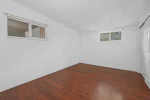 Unfurnished bedroom featuring a closet and dark wood-style flooring